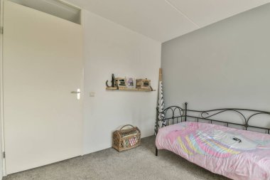 Beyaz çarşaflı rahat bir yatak ve lambasıyla pencere ve balkon kapısının yakınına yerleştirilmiş aydınlık yatak odası.