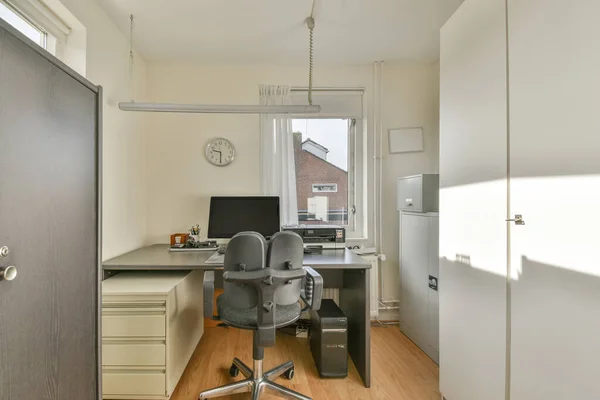 Interior of light home office with wooden desk and shelf rack near window with curtains