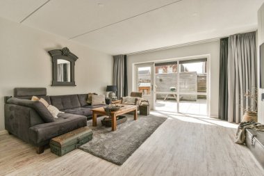 Konforlu kanepe döşenmiş oturma odasının rahat iç tasarımı ve modern tavan arası dairesinin beyaz duvarları ve sütunlarıyla döşenmiş ahşap masa.