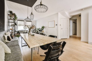 Geniş pencereli, beyaz duvarlı, rahat kanepe ve halı döşeli, geniş oturma odasının şık iç tasarımı.