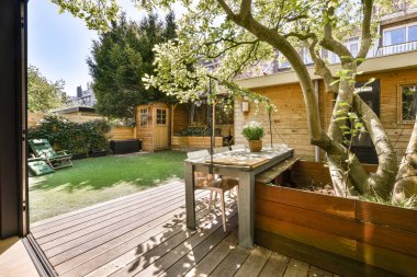 Oturma alanı ve ahşap çitlerin yanındaki küçük bahçesi olan düzgün asfaltlı bir avlu.