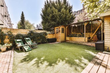 Oturma alanı ve ahşap çitlerin yanındaki küçük bahçesi olan düzgün asfaltlı bir avlu.