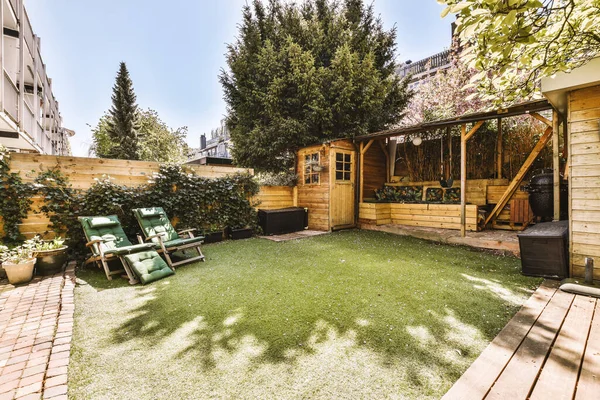 Oturma alanı ve ahşap çitlerin yanındaki küçük bahçesi olan düzgün asfaltlı bir avlu.