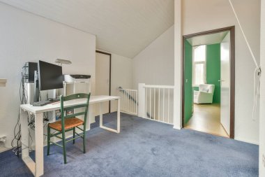 Modern apartmandaki hafif iş yerinde bilgisayar monitörleri ve beyaz tahtanın olduğu masanın yanına konforlu sandalye