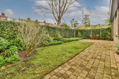 Oturma alanı ve ahşap çitlerin yanındaki küçük bahçesi olan düzgün asfaltlı bir avlu.