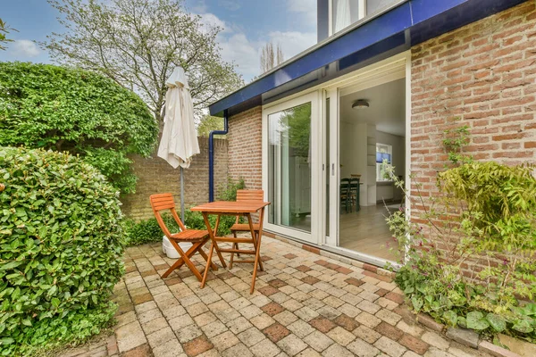 Neat paved patio with sitting area and small garden near wooden fence