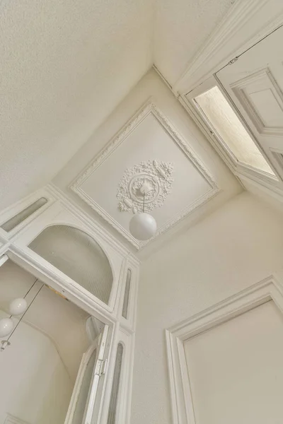 From below classic plaster floral ornament of medallion decorating ceiling above elegant chandelier at home