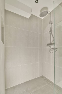 Duş muslukları cam bölmenin yanındaki fayanslı duvara bağlı ve evdeki tuvaletteki süs pervazı.