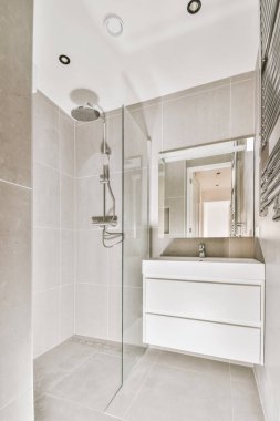 Sinks with mirrors and shower box with glass door in modern bathroom with white tiled walls