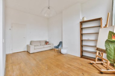 Sandalyeleri ve vazosu olan eski püskü ahşap masa modern apartmanda dekorasyonlu aydınlık duvarlara karşı rahat kanepenin yanında.