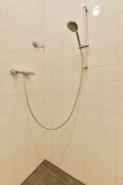 Duş muslukları cam bölmenin yanındaki fayanslı duvara bağlı ve evdeki tuvaletteki süs pervazı.