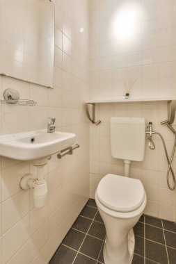 Lavabolu ve duvarlı, beyaz duvarlı ve kareli tuvaletli dar bir tuvalet.