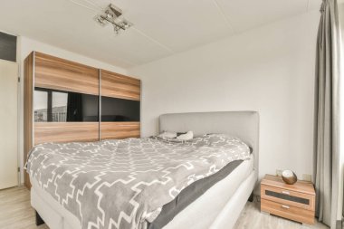 Yatak odasının iç tasarımı, yatak odası ve ahşap gardırop modern dairenin penceresinin kenarına yerleştirilmiş.