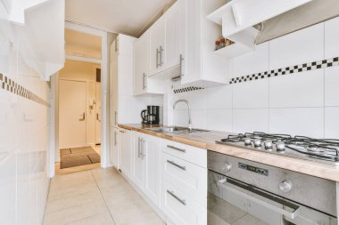 Minimalist tarzı beyaz mobilyalı, lavabolu ve sobalı bir ev mutfağı.