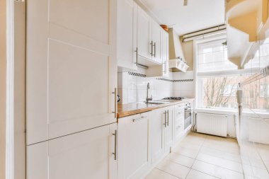 Minimalist tarzı beyaz mobilyalı, lavabolu ve sobalı bir ev mutfağı.