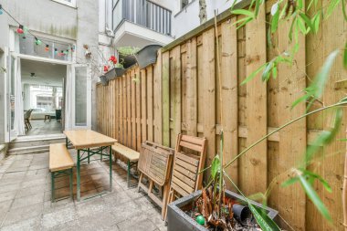 Neat paved patio with sitting area and small garden near wooden fence