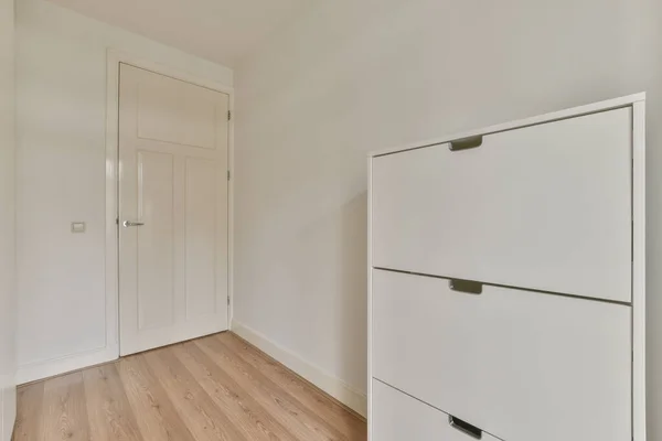 现代化的橱柜和老式的木箱放在宽敞的房间里靠近门和柳条筐的地方 有白色的墙壁和木制的地板 — 图库照片