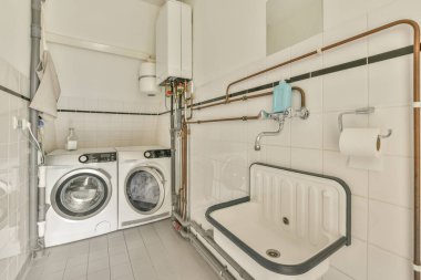 Evdeki modern tuvalette asılı duran banyo musluğu ile duvar arasındaki cam bölme.