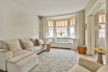 Şık bir oturma odası, rahat bir kanepe ve modern bir dairede masanın etrafına yerleştirilmiş yastıklı koltuklar.