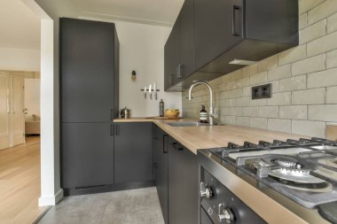 Stüdyo dairesinin modern minimalist tarzı iç tasarımı açık beyaz mutfak ve yemek masası ve sandalyeleri tavan arası lambasıyla aydınlatılmış.