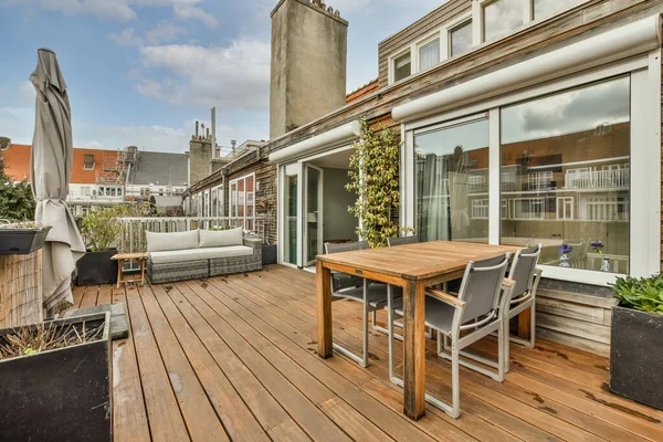 Neat paved patio with sitting area and small garden near wooden fence