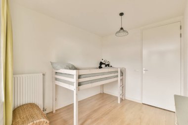 Bebek beşiği ve pencerenin yanındaki koltuğu olan beyaz odanın içi. Gün ışığında mavi çekmecelerle dolu.