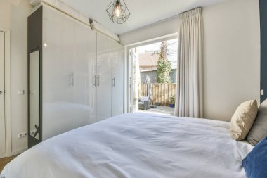 Yatak odasının iç tasarımı, yatak odası ve ahşap gardırop modern dairenin penceresinin kenarına yerleştirilmiş.
