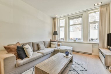 Modern apartmandaki dekorasyonlu ve televizyonlu, rahat koltuğun yanına yerleştirilmiş eski püskü ahşap masa.