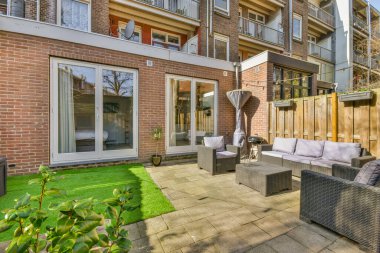 Oturma alanı ve ahşap çitlerin yanındaki küçük bahçesi olan düzgün asfaltlı bir avlu.