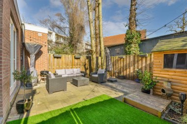 Neat paved patio with sitting area and small garden near wooden fence