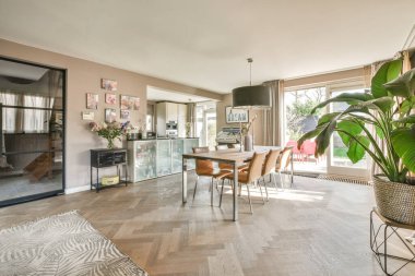 TV 'nin yanındaki koltuklar ve masa, çağdaş apartmandaki geniş odalı yemek alanına karşıdır.