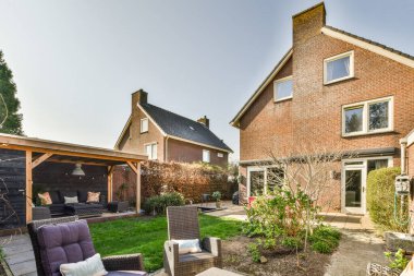 Oturma alanı ve ahşap çitlerin yanındaki küçük bahçesi olan düzgün asfaltlı bir avlu.