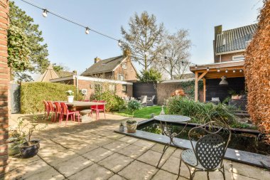 Oturma alanı ve ahşap çitlerin yanındaki küçük bahçesi olan düzgün asfaltlı bir avlu.