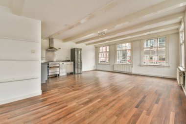 Pencereleri ve ahşap parke zemini olan boş beyaz mutfağın içi.