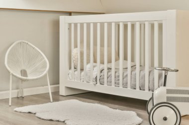 Bebek beşiği ve pencerenin yanındaki koltuğu olan beyaz odanın içi. Gün ışığında mavi çekmecelerle dolu.