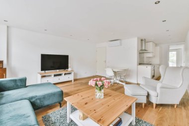 Günümüz minimalist tasarımı. Hafif stüdyo dairesinin ahşap masası ve oturma odası ile beyaz duvarları ve parke zemini arasında yemek masası ve sandalyeleri var.