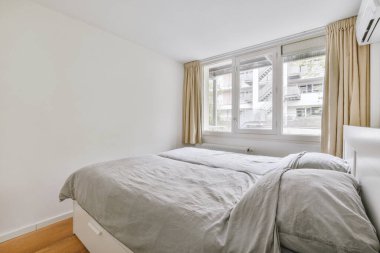 Yatak odasının iç tasarımı, yatak odası ve ahşap gardırop modern dairenin penceresinin kenarına yerleştirilmiş.