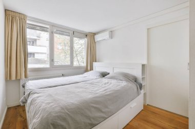 Yatak odasının iç tasarımı, yatak odası ve ahşap gardırop modern dairenin penceresinin kenarına yerleştirilmiş.