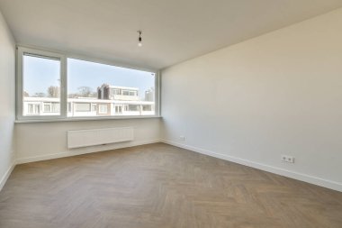 Evdeki boş ışık odasında, beyaz duvardaki plastik pencere ve radyatör.