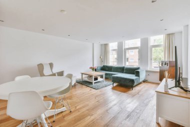 Modern apartmandaki dekorasyonlu ve televizyonlu, rahat koltuğun yanına yerleştirilmiş eski püskü ahşap masa.
