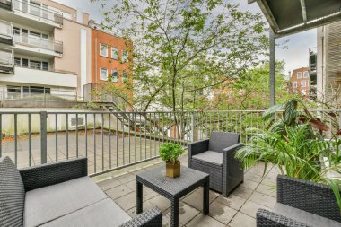 Oturma alanı ve ahşap çitlerin yanındaki küçük bahçesi olan düzgün asfaltlı bir avlu.