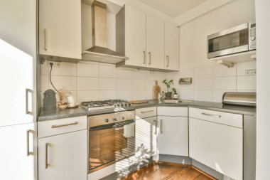 Günümüz mutfağının içinde modern dairenin yemek alanı yakınında şık siyah dolaplar ve aletler var.