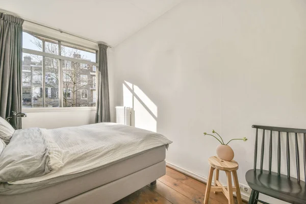 白い壁と柔らかい居心地の良いベッドと照明付きの日光のミニマリストスタイルの棚と小さなマンサードベッドルームのモダンなインテリアデザイン — ストック写真