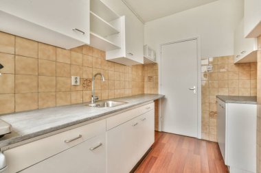 İyi organize edilmiş küçük bir ev mutfağı pencerenin altında lavabo, sobalı hafif mobilyalar ve kentsel apartmanda buzdolabı var.