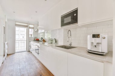 Minimalist tarzı beyaz mobilyalı, lavabolu ve sobalı bir ev mutfağı.