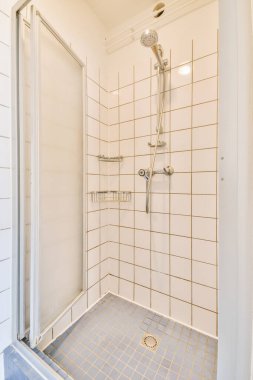 Duş muslukları cam bölmenin yanındaki fayanslı duvara bağlı ve evdeki tuvaletteki süs pervazı.