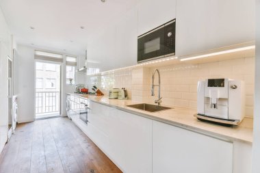 Minimalist tarzı beyaz mobilyalı, lavabolu ve sobalı bir ev mutfağı.