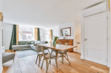 Günümüz minimalist tasarımı. Hafif stüdyo dairesinin ahşap masası ve oturma odası ile beyaz duvarları ve parke zemini arasında yemek masası ve sandalyeleri var.