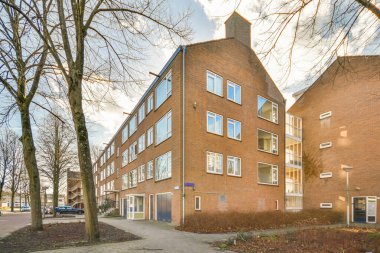 Ağaçlar ve fenerlerle dolu boş bir kaldırım sokağından tuğla evler manzarası