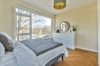 Yatak odasının iç tasarımı, yatak odası ve ahşap gardırop modern dairenin penceresinin kenarına yerleştirilmiş.